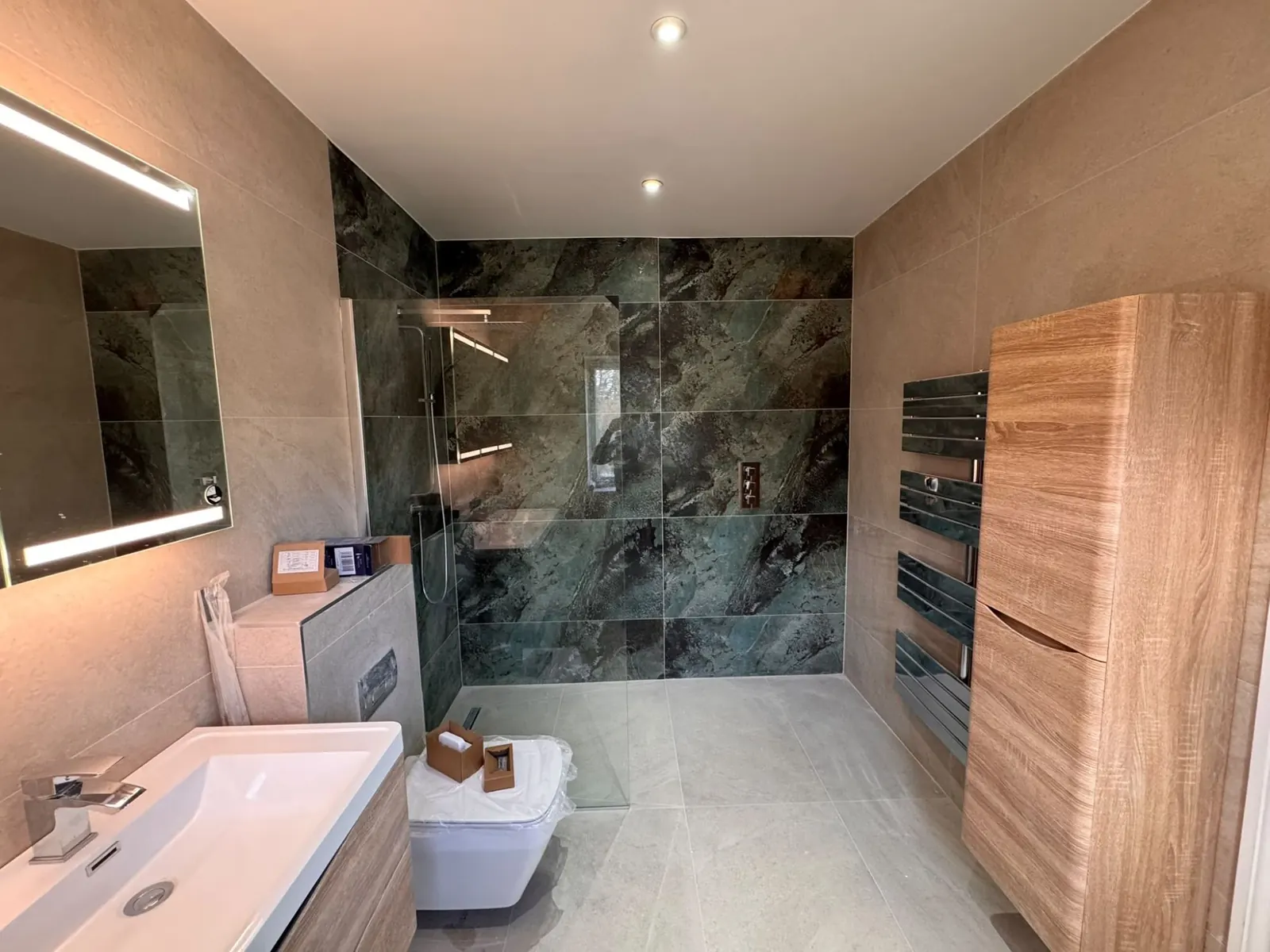 Walk-in shower with a green stone-effect feature wall, oak-effect cabinets and heated towel rail