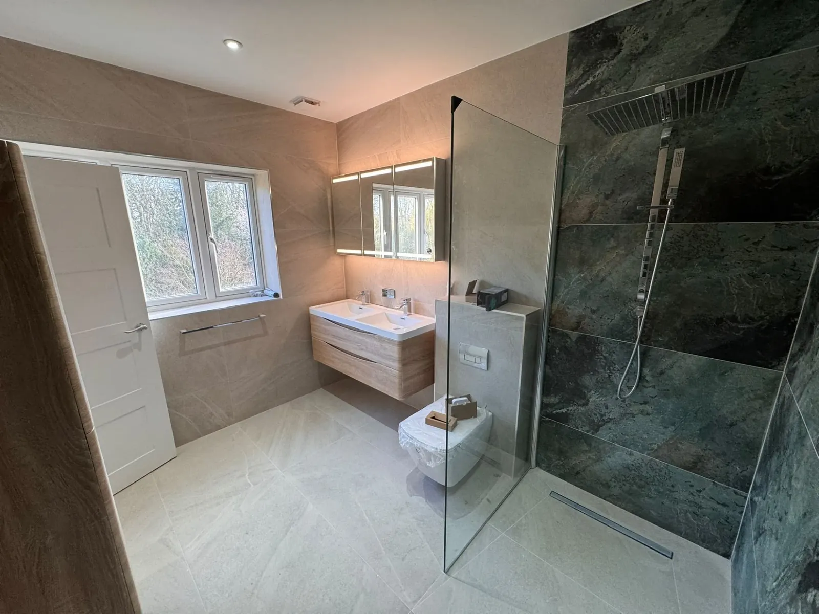 Bathroom with a walk-in rainfall shower, green stone-effect tiles and a double vanity