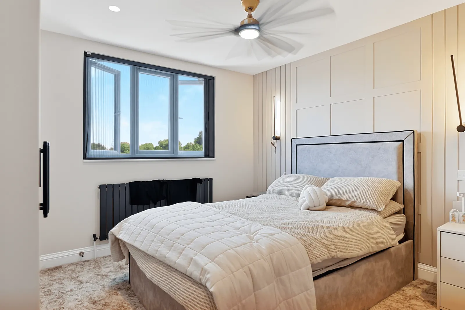 Bedroom with a full-height panelled wall, wall lights and a ceiling fan