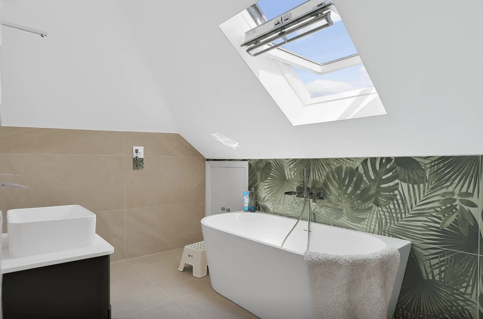 Loft bathroom with a freestanding bath, skylight and palm-print wall tiles