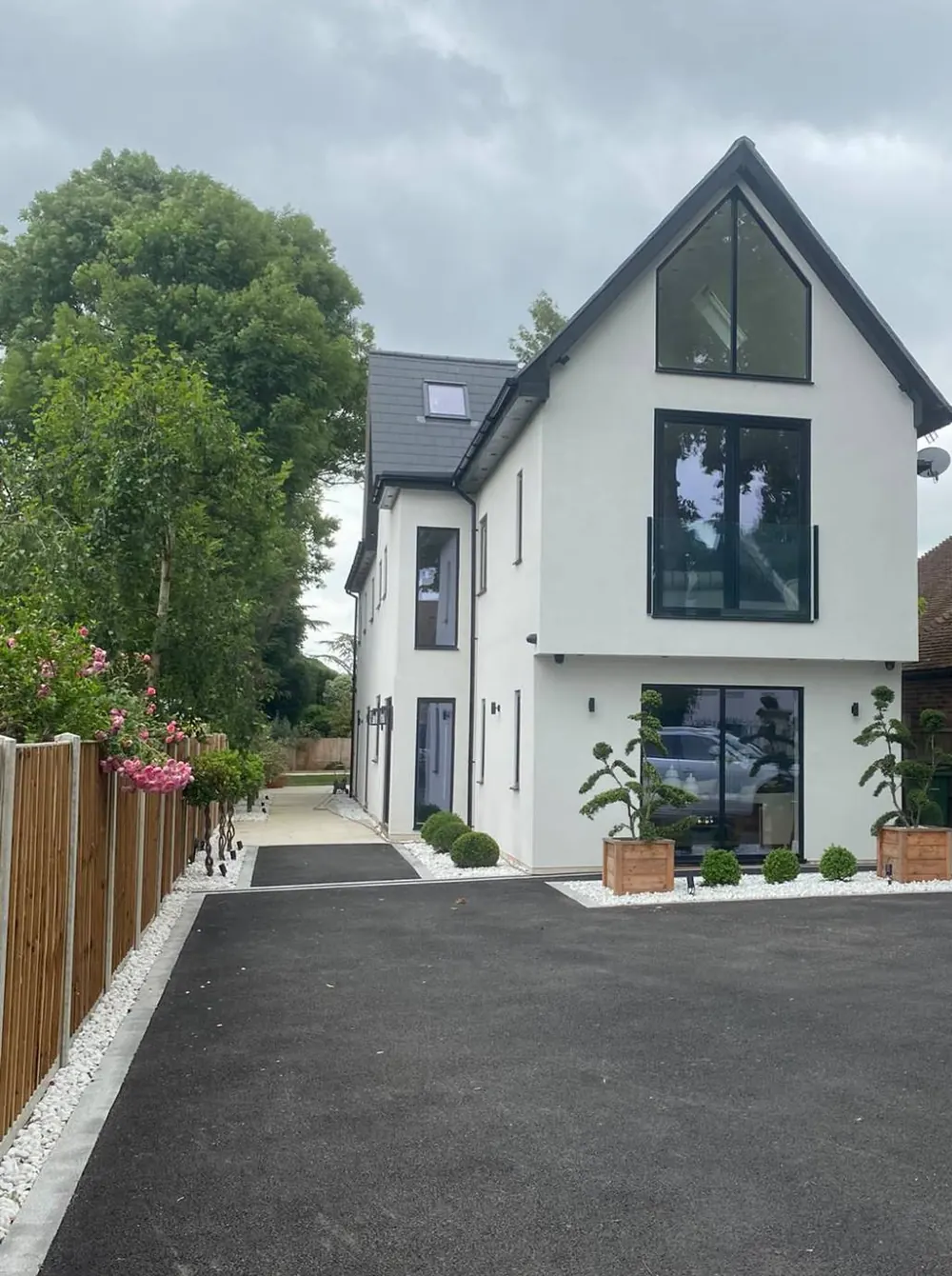 Three-storey white new-build house with a glazed gable, Juliet balcony and new driveway
